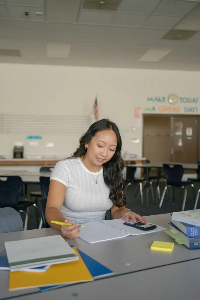 A student writes at a classroom desk.