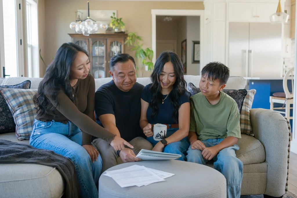 A family reviews planning materials together on a sofa.
