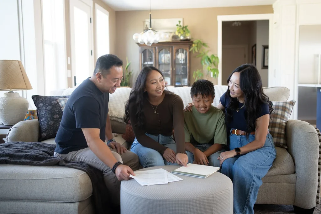 Four people review planning materials together at home.