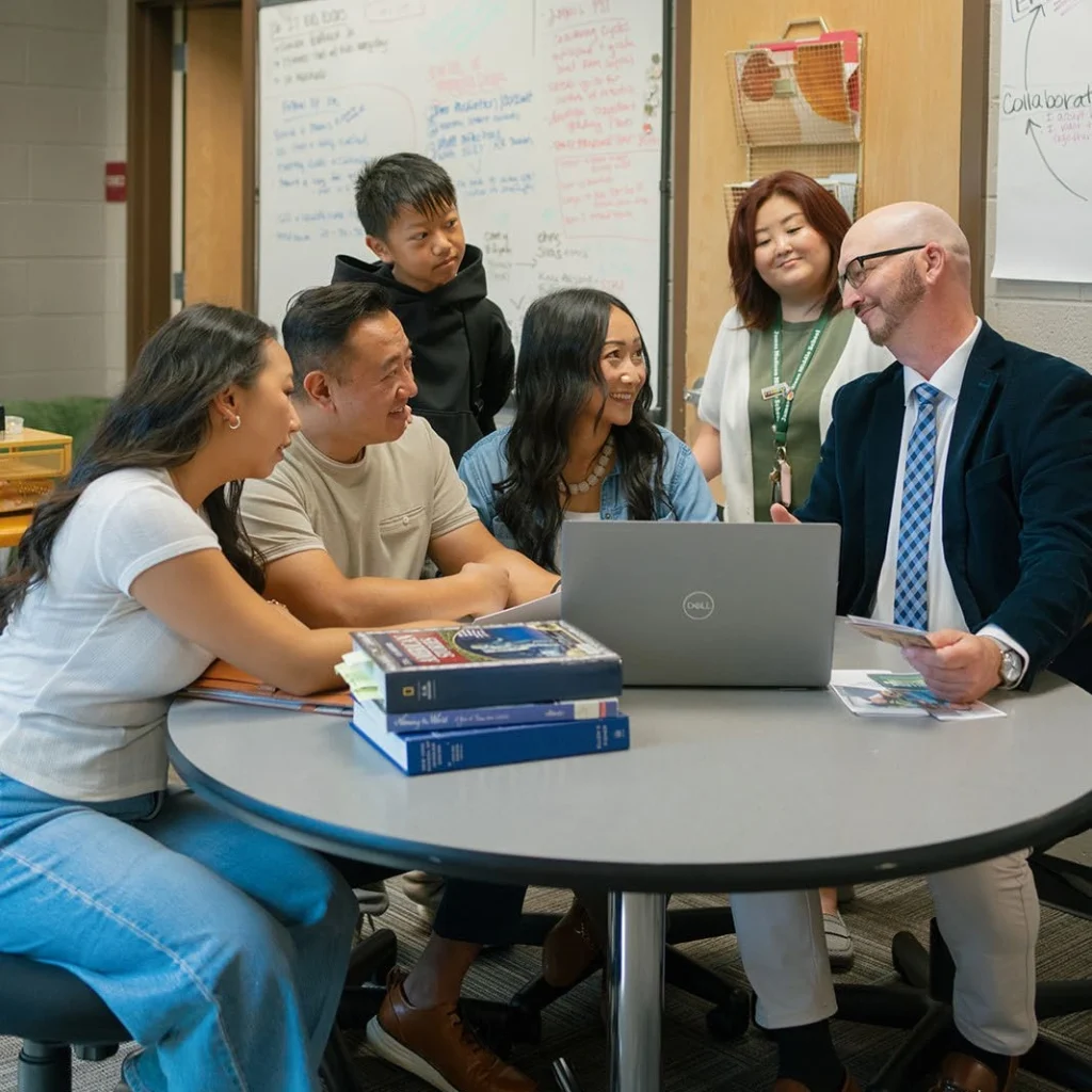 A student and family meet with school staff around a table.